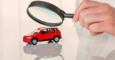 Человек рассматривает автомобиль под лупой