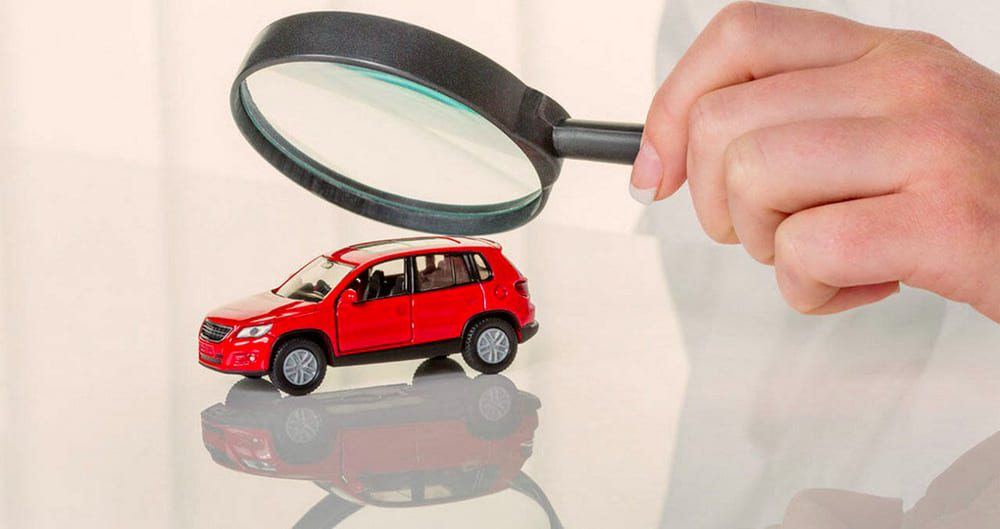 Человек рассматривает автомобиль под лупой