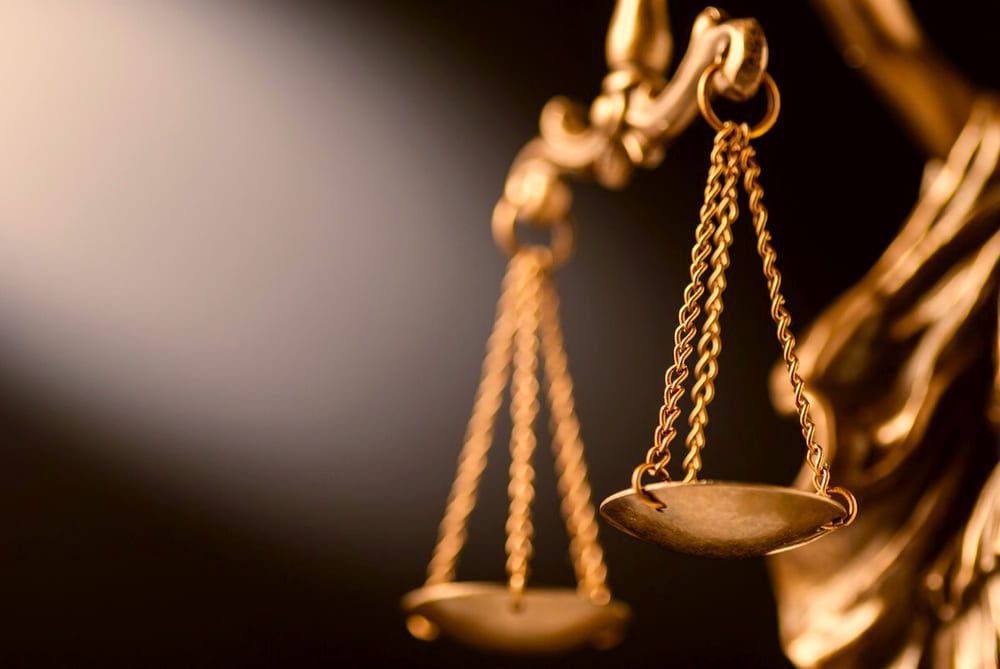 Золотые весы правосудия на размытом темном фоне