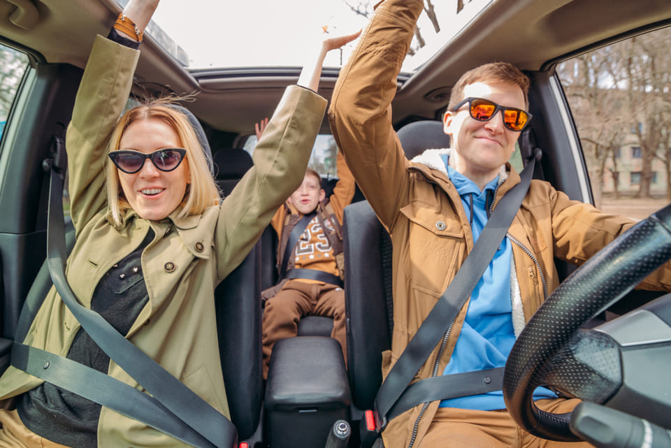 Семья с ребенком едет в собственном автомобиле. Все пристегнуты и счастливы, что едут в отпуск