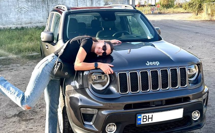 Счастливая девушка обнимает автомобиль марки Jeep, который она купила через компанию W8 Shipping